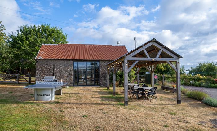 Grassy terrace outside stone barn and open barn with ping pong table